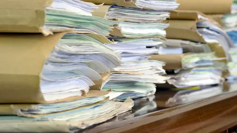 heap fo paper folders on wooden desk