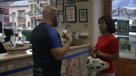 Pla mitj&agrave; de l'encarregat del lloguer de bicicletes de Camp Base de Ll&iacute;via, parlant amb una persona interessada en fer una ruta tur&iacute;stica i on es veuen de fons cartells de l'acci&oacute; "Welcome Summer Cerdanya". Imatge del 25 de juny de 2020 (Horitzontal).