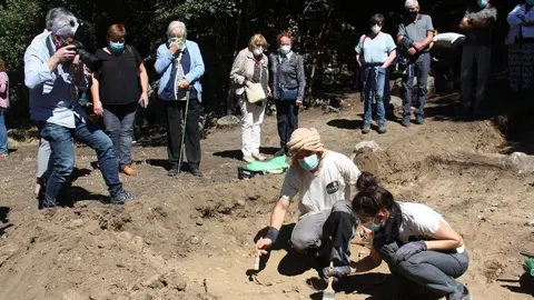 Pla obert de dos arque&ograve;legs analitzant el qu&egrave; han trobat en l'excavaci&oacute; d'una fossa de la Guerra Civil a Sorpe, a l'Alt &Agrave;neu (Pallars Sobir&agrave;), i familiars de les v&iacute;ctimes que hi hauria enterrades mirant-ho darrere, el 2 de setembre de 2020 (Horitzontal).