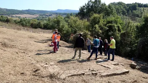 En primer pla restes de les parets de la casa residencial de la vil&middot;la romana de Llor&iacute;s i al fons els arque&ograve;legs explicant el jaciment el dia 30 de setembre del 2020. (horitzontal)