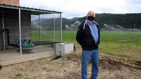 Pla general del president de la comunitat de regants de Peramola-Bassella, Joan Puig, a la seva finca, on es veu al fons la canonada i el reg per aspersi&oacute; per on surt l'aigua. Imatge del 26 de novembre de 2020 (Horitzontal).