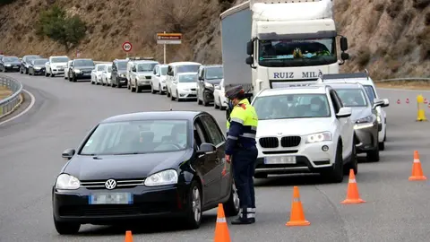 Pla obert on es veu un mosso parant un dels vehicles que accedien al t&uacute;nel del Cad&iacute; (C-16) en direcci&oacute; sud i la cua de cotxes al darrere en el segon dia de confinament perimetral de la Cerdanya. Imatge del 24 de desembre de 2020 (Horitzontal).