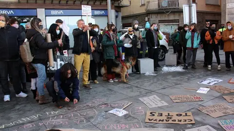 Pla obert on es veuen diversos manifestants protestant a la pla&ccedil;a de l'Ajuntament de Puigcerd&agrave; pel confinament perimetral de la Cerdanya, on es veuen les pancartes al terra i una persona escrivint amb guix. Imatge del 31 de desembre de 2020 (Horitzontal).