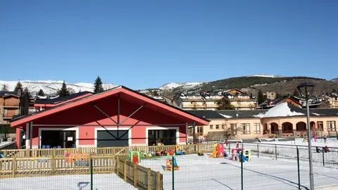 Pla obert on es veu part de l'edifici de la nova Escola Jaume I de Ll&iacute;via (Cerdanya) i la Llar d'infants Els Esquirolets amb alguns alumnes jugant amb la neu al pati i l'antiga escola al fons. Imatge de l'11 de gener de 2021 (Horitzontal).