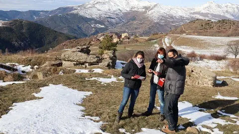 Pla general dels responsables del Museu de Camins mirant els tr&iacute;ptics d'una ruta de senderisme de la Guerra Civil a la Vall de Siarb on es veu darrere els b&uacute;nquers i el nucli de Vilamur, a Soriguera (Pallars Sobir&agrave;), el 20 de gener de 2021 (Horitzontal).