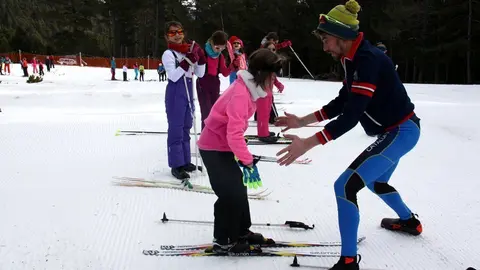Pla general on es veu un dels monitors del programa Esport Blanc Escolar ajudant a una de les alumnes que estan aprenent esqu&iacute; de fons a Aransa, a Lles de Cerdanya. Imatge del 13 de gener de 2020 (Horitzontal).