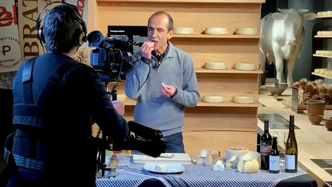 Pla obert del gastr&ograve;nom Pep Palau tastant un formatge durant la gravaci&oacute; d'un nou v&iacute;deo per al canal virtual de la Fira de Sant Ermengol de la Seu d'Urgell i on es veu tamb&eacute; el c&agrave;mera encarregat de l'audiovisual, el 28 de gener de 2021 (Horitzontal).