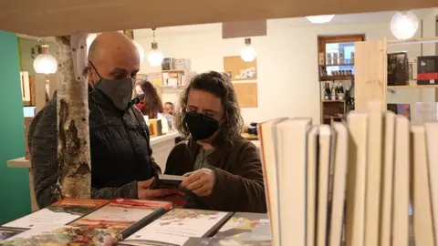 Pla mig de dos clients a la llibreria NaturaLlibres d'Alins fullejant algun llibre el 25 de gener del 2021. (horitzontal)