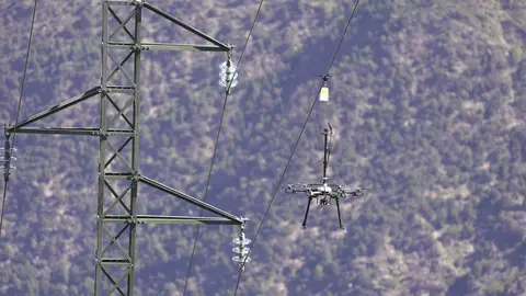 Pla de detall d'un dron col&middot;locant senyalitzaci&oacute; a una l&iacute;nia el&egrave;ctrica per evitar l'impacte de les aus al municipi de Rialp el 17 de maig del 2021 (horitzontal)