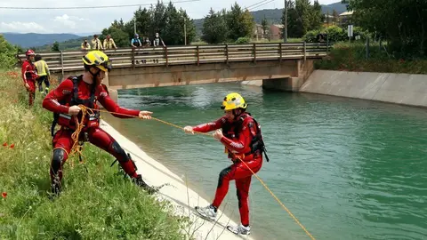Pla general de dos bombers fent pr&agrave;ctiques de rescat aqu&agrave;tic al canal de Gavet. Un bombers estira amb una coda a un altre que simulava haver caigut. Imatge del 28 de maig del 2021. (Horitzontal)