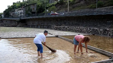 Pla general de dos persones trencant la crosta de la sal a una de les salines en funcionament de Gerri de la Sal. Imatge del 3 d'agost del 2021. (Horitzontal)