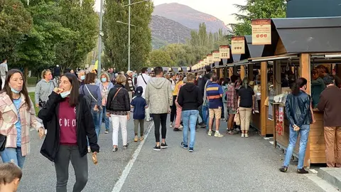 Pla obert de la zona exterior on s'han ubicat les parades del sector del formatge de la Fira de Sant Ermengol de la Seu d'Urgell on es veu en primer terme dues noies tastant un tros de formatge. Imatge publicada el 17 d'octubre de 2021. (Horitzontal)