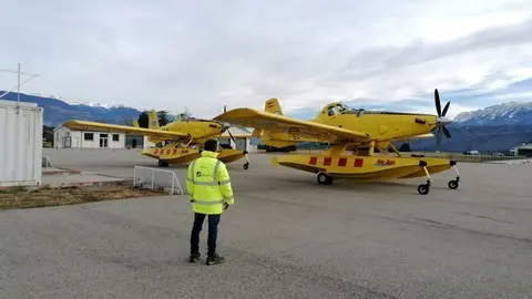 Pla obert on es veu un operari, d'esquena, amb els dos avions de vigil&agrave;ncia i atac que els Bombers tenen a la base de l'aeroport d'Andorra-La Seu. Imatge publicada el 3 de desembre de 2021. (Horitzontal)