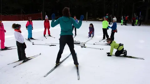 Pla general d'un grup d'alumnes del programa d'Esport Blanc Escolar amb una de les monitores a l'estaci&radic;&ge; d'esqu&radic;&ne; de fons d'Aransa, a Lles de Cerdanya. Imatge del 13 de gener de 2020 (Horitzontal).