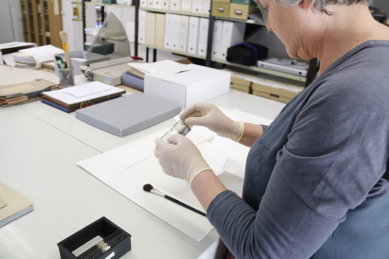 A la dreta de la imatge una treballadora de l'arxiu manipulant una des les plaques. Imatge del 11 d'abril de 2017. (horitzontal)