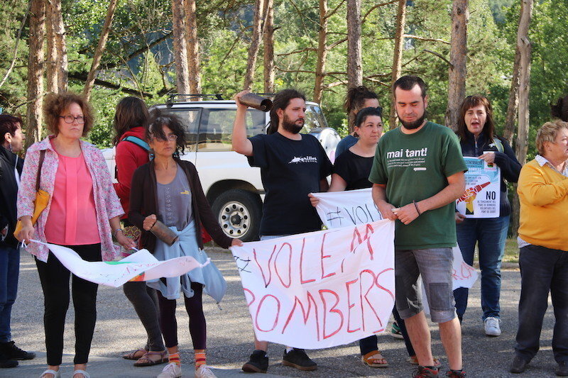 Imatge d'un grup de manifestants a l'exterior del Parc de Bombers del Pont de Suert amb pancartes reivindicatives i esquellots. Imatge del 29 de juny del 2017. (horitzontal)