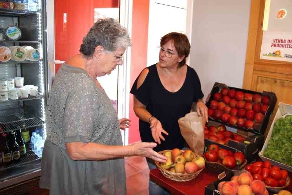 Pla de detall d'una de les responsables de Mas Cal Cintó, a la dreta, venent pomes de muntanya de l'explotació a la zona de l'agrobotiga, el 24 de setembre de 2018 (Horitzontal).