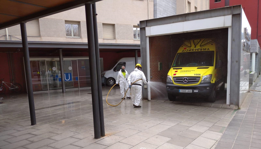 Pla general on es veuen dos operaris duent a terme tasques de desinfecció a l'exterior de l'edifici del Sant Hospital de la Seu d'Urgell. Imatge facilitada per l'Ajuntament de la Seu d'Urgell el 27 de març de 2020 (Horitzontal).