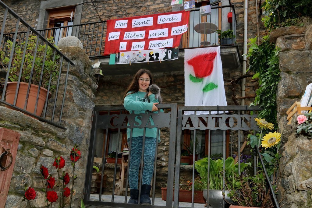 Pla general d'una façana, del municipi de Sort, engalanada per Sant Jordi amb una nena dins el patí de casa el 24 d'abril del 2020. (horitzontal)