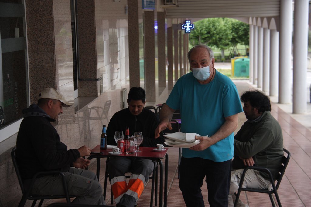Pla general d'una de les taules d'una terrassa d'un bar d'Oliana (Alt Urgell) on es veuen tres persones assegudes i el propietari de l'establiment recollint part de la taula en el primer dia de la fase 1 de desescalada, l'11 de maig de 2020 (Horitzontal).