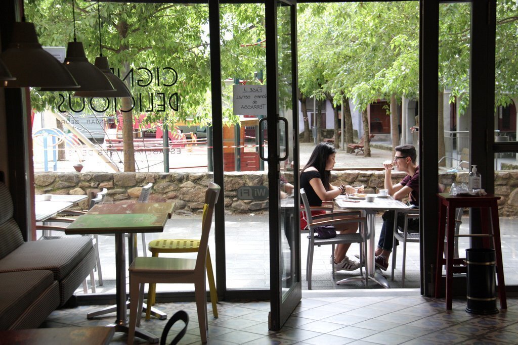 Pla de detall d'una part d'una cafeteria de la Seu d'Urgell on es veu una taula buida a l'interior del local i una ocupada a la zona de la terrassa el primer dia de la fase 2 de la desescalada. Imatge del 25 de maig de 2020 (Horitzontal).