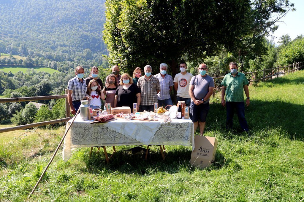 Pla general on es veuen els productors de l'entorn del Parc Natural de l'Alt Pirineu que s'han unit en una associació darrere una taula on hi han alguns dels productes que elaboren. Imatge del 30 de juny de 2020 (Horitzontal).