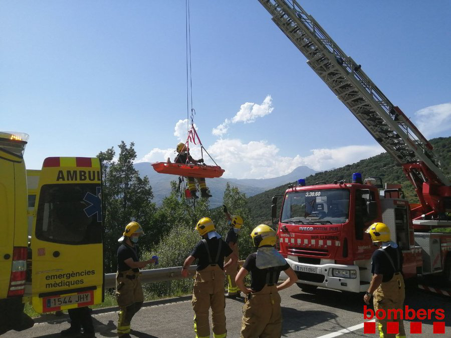 La grupa dels Bombers transporta el conductor d'una furgoneta penjada en uns arbres després de caure per un barranc el 21 de juliol del 2020. Pla general. (Horitzontal)