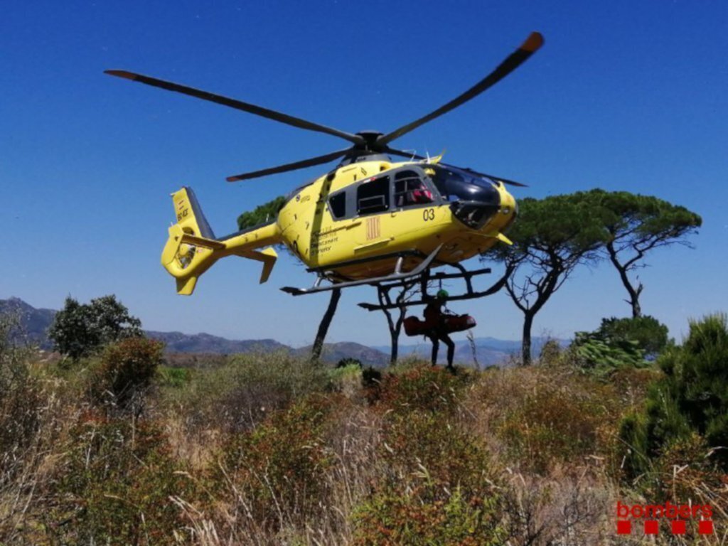 Pla mitjà d'un Bomber dels GRAE amb la llitera carregant l'home a l'helicòpter del SEM aquest diumenge 19 de juliol de 2020 a El Port de la Selva. (Horitzontal)