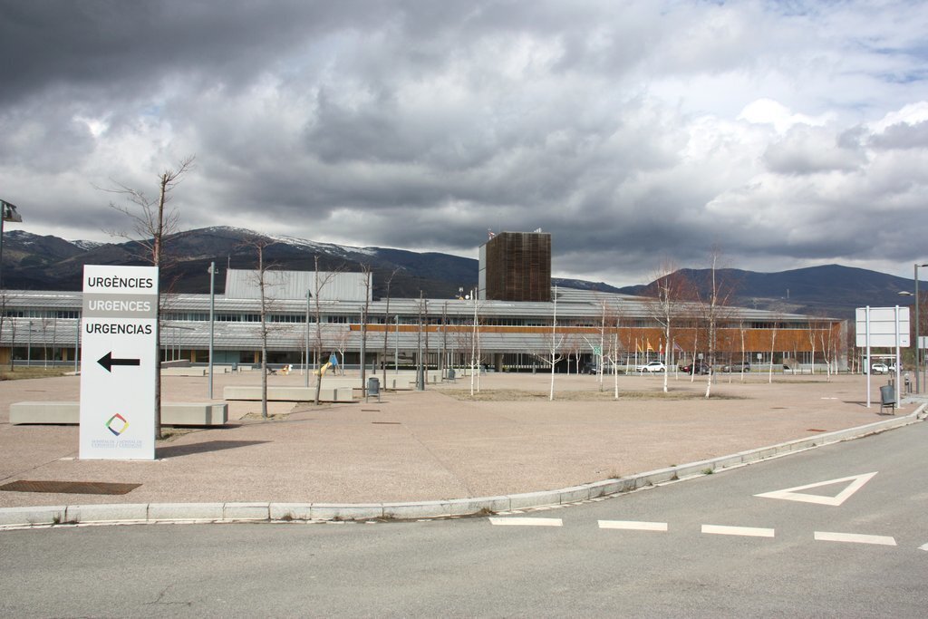 Pla general de l'exterior de l'edifici de l'Hospital de Cerdanya, on es veu en primer terme un cartell que indica on està la zona d'Urgències. Imatge del 13 de març de 2020 (Horitzontal).