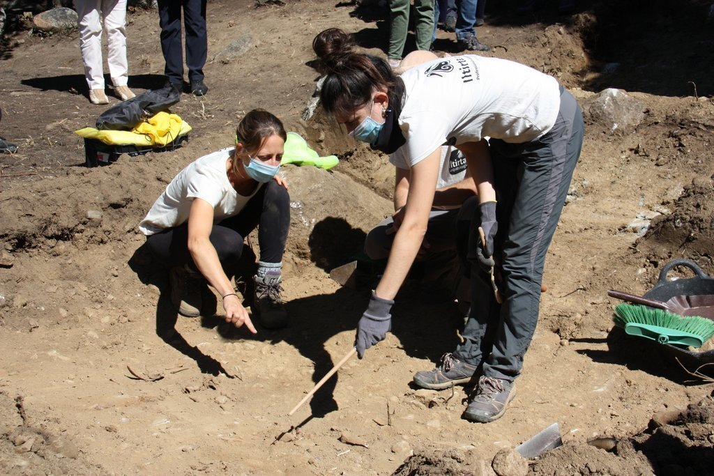 Pla obert on es veuen dues arqueòlogues assenyalant la zona que han de continuar explorant i que forma part en l'excavació d'una fossa de la Guerra Civil a Sorpe, a l'Alt Àneu (Pallars Sobirà), el 2 de setembre de 2020 (Horitzontal).