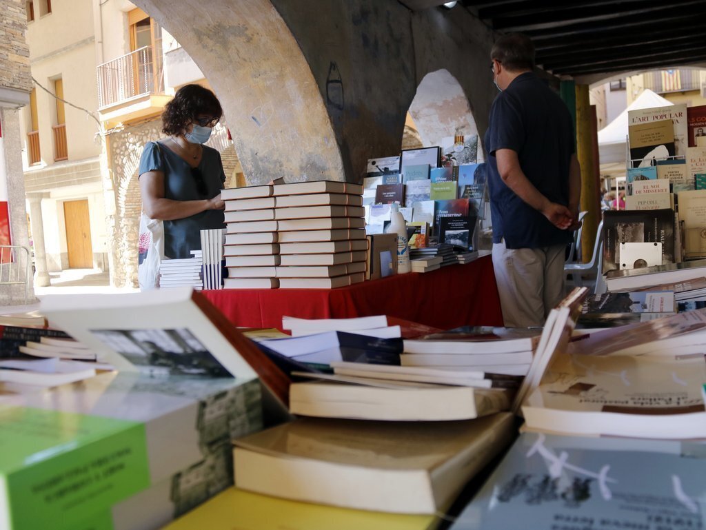 Pla obert d'una dona fullejant un llibre en una parada a la 24a Fira del Pirineu que se celebra a Organyà, el 5 de setembre de 2020. (Horitzontal)