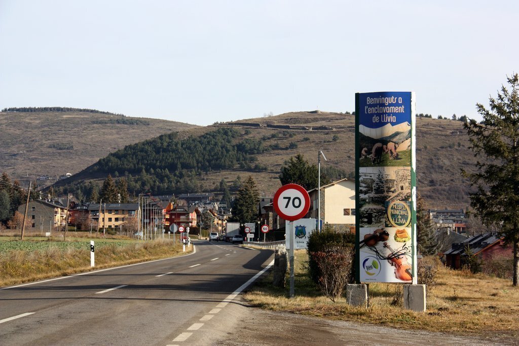 Pla general de l'entrada a Llívia (Cerdanya) des de Puigcerdà on hi ha un cartell que dona la benvinguda a l'enclavament. Imatge del 22 de desembre de 2020 (Horitzontal).