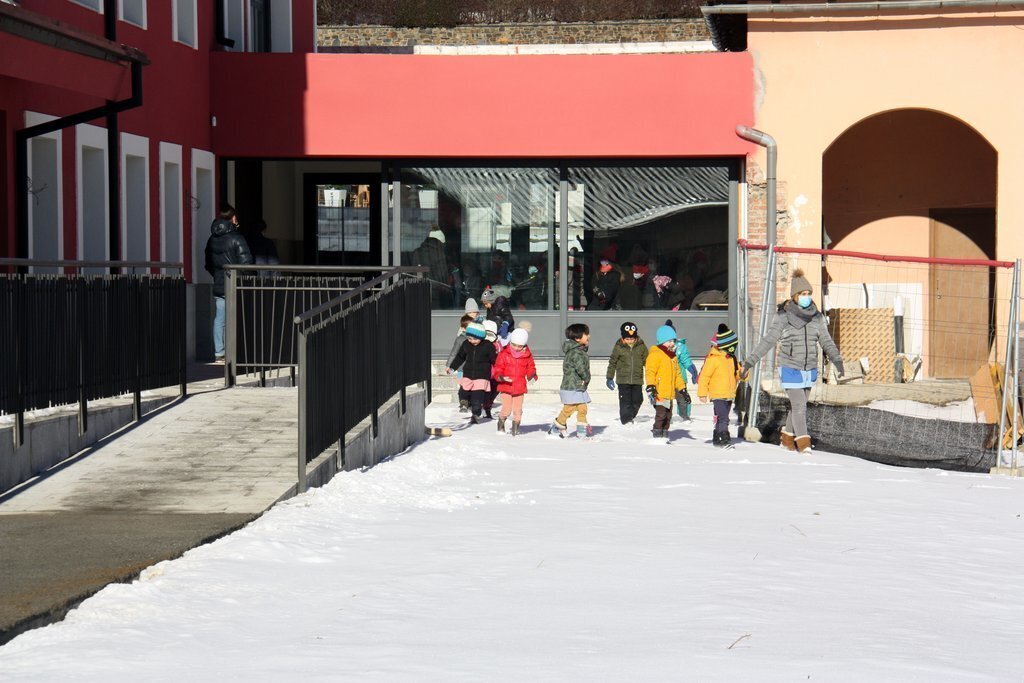 Pla obert d'alumnes de l'Escola Jaume I de Llívia (Cerdanya) sortint al pati des del nou edifici. Imatge de l'11 de gener de 2021 (Horitzontal).