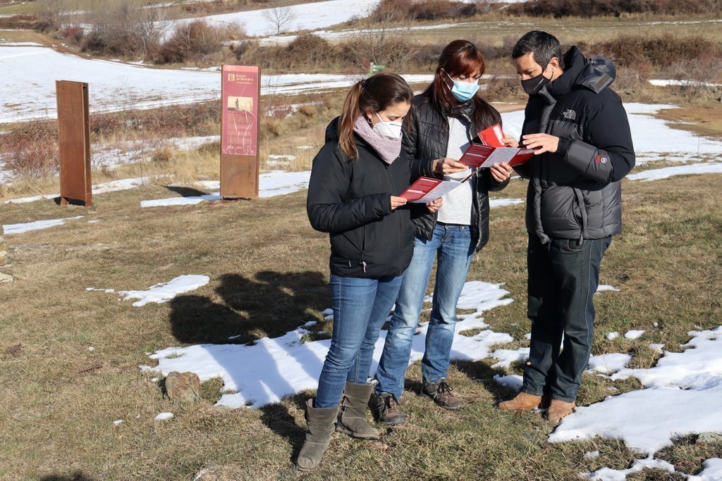 Pla obert dels responsables del Museu de Camins mirant els tríptics d'una ruta de senderisme de la Guerra Civil a la Vall de Siarb on es veu darrere cartells sobre els búnquers de Vilamur, a Soriguera (Pallars Sobirà), el 20 de gener de 2021 (Horitzontal)