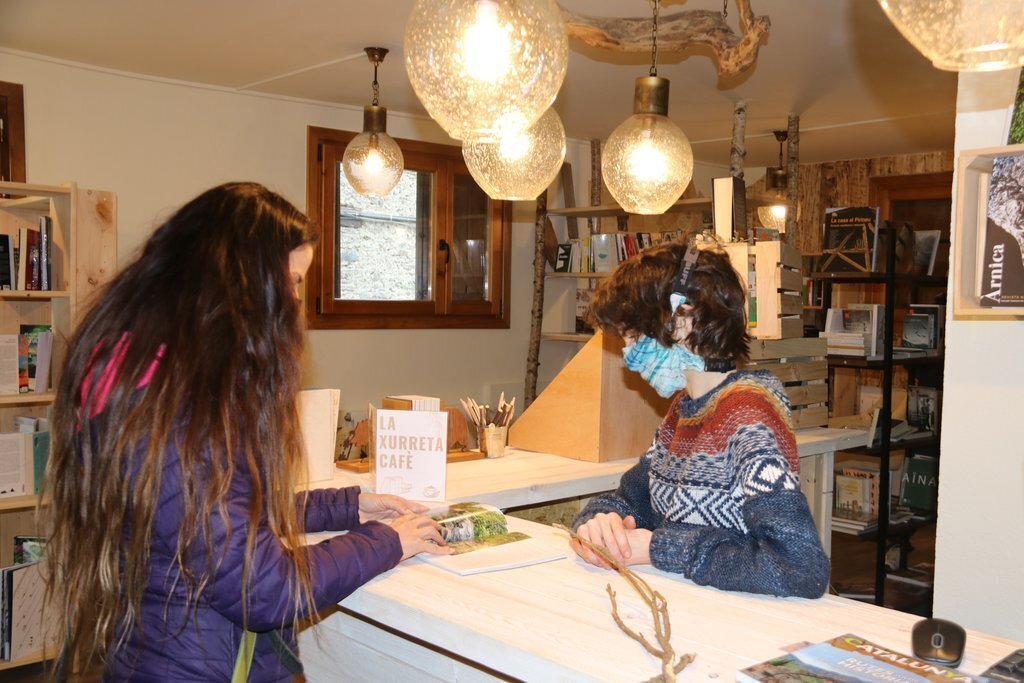 Pla mig de la llibretera de NaturaLlibres atenent a una clienta el 25 de gener del 2021. (horitzontal)