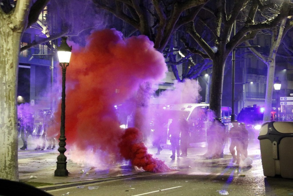 Pla obert dels Mossos d'Esquadra, en fila, a l'avinguda Blondel de Lleida, ocultats parcialment pel contingut d'un pot de fum llençat pels manifestants. Imatge del 16 de febrer de  2021. (Horitzontal)