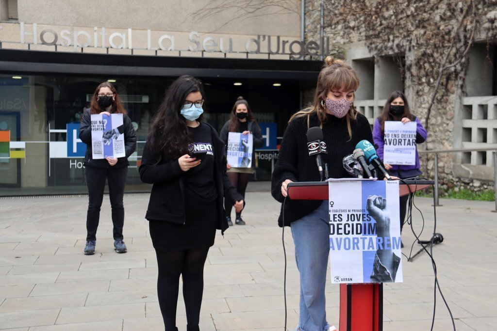 Pla americà d'una militant d'Arran a l'Alt Urgell, la Laia, presentant la campanya 'Les joves decidim, avortarem!' davant la Fundació Sant Hospital de la Seu d'Urgell on no es duu a terme aquesta pràctica. Imatge del 2 de març de 2021 (Horitzontal).