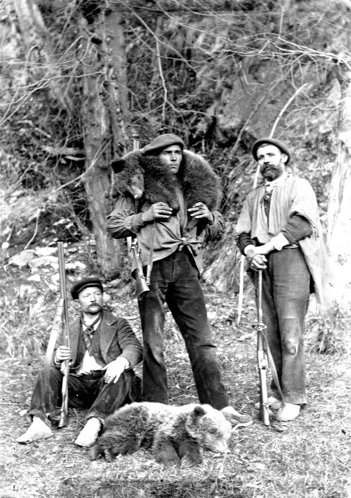 Foto antiga d'una estampa de la cacera de l'ós. Dempeus Jaume Arnalot, el Tort d'Alòs, amb l'ossall a les espatlles, i el seu pare Pere assegut a la seva dreta. (Vertical)