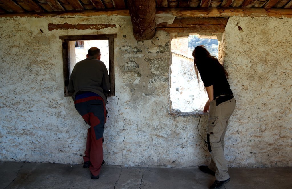 Pla de detall de dos dels socis de la cooperativa La Tremolina mirant per la finestra de l'era que han adquirit. Imatge del 9 de març del 2021. (horitzontal)