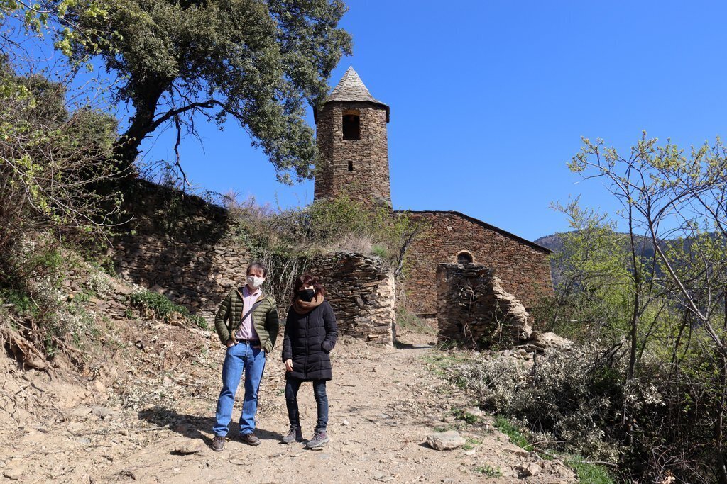 Pla obert de la delegada de Patrimoni Cultural del Bisbat d'Urgell, Clara Arbués, i el tècnic de Patrimoni Cultural del Consell de l'Alt Urgell, Carles Gascón, passejant per l'entorn de l'església de Solanell. Imatge del 16 d'abril de 2021 (Horitzontal).