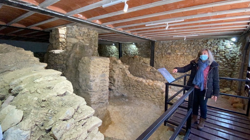 Pla obert de Glòria Santana, regidora de l'Ajuntament d'Isòvol, mostrant les restes arqueològiques d'un carrer del segle XVI que es poden veure al Centre d'Interpretació del País dels Esterregalls. Imatge del 8 d'abril de 2021 (Horitzontal).