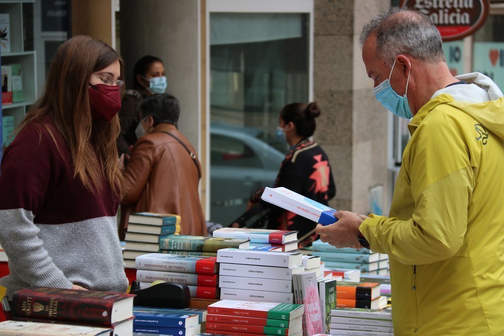 Pla tancat d’un home comprant un llibre en una de les parades en la primera jornada de Sant Jordi a Valls. Imatge del 22 d’abril del 2021 (Horitzontal).