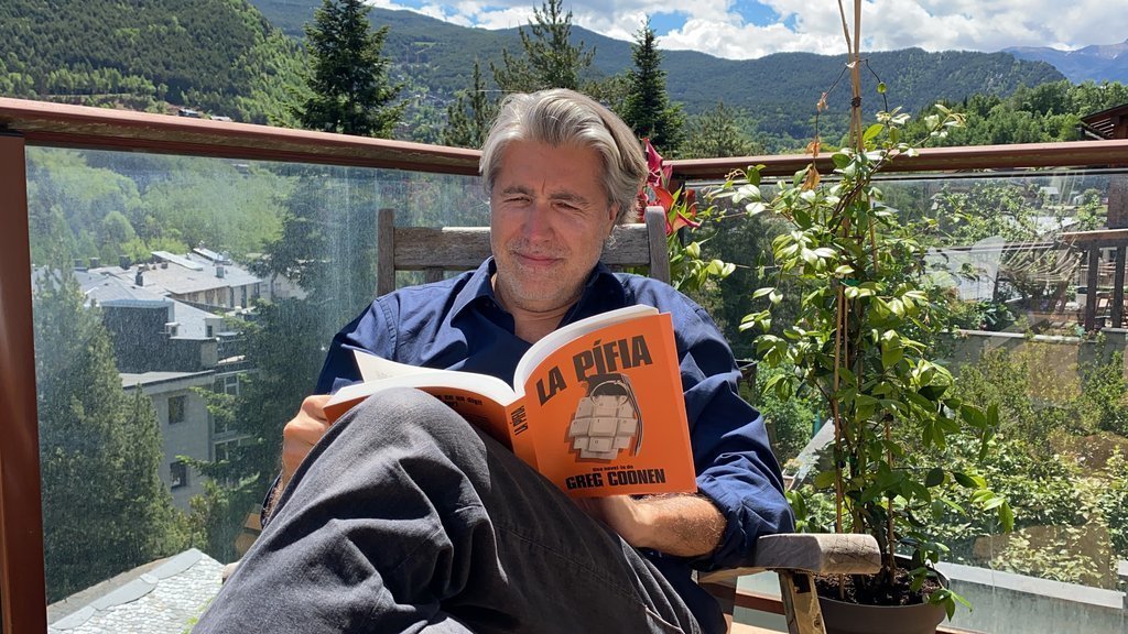 Pla mitjà de l'escriptor Greg Coonen fullejant el seu llibre 'La Pífia' a l'exterior de casa seva, a La Massana (Andorra). Imatge del 2 de juny de 2021. (Horitzontal)