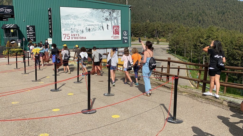 Pla obert d'un grup d'alumnes de l'Escola Bac de Cerdanya d'Alp dirigint-se a un dels punts de l'estació de La Molina per recollir residus. Imatge del 16 de juny de 2021. (Horitzontal)