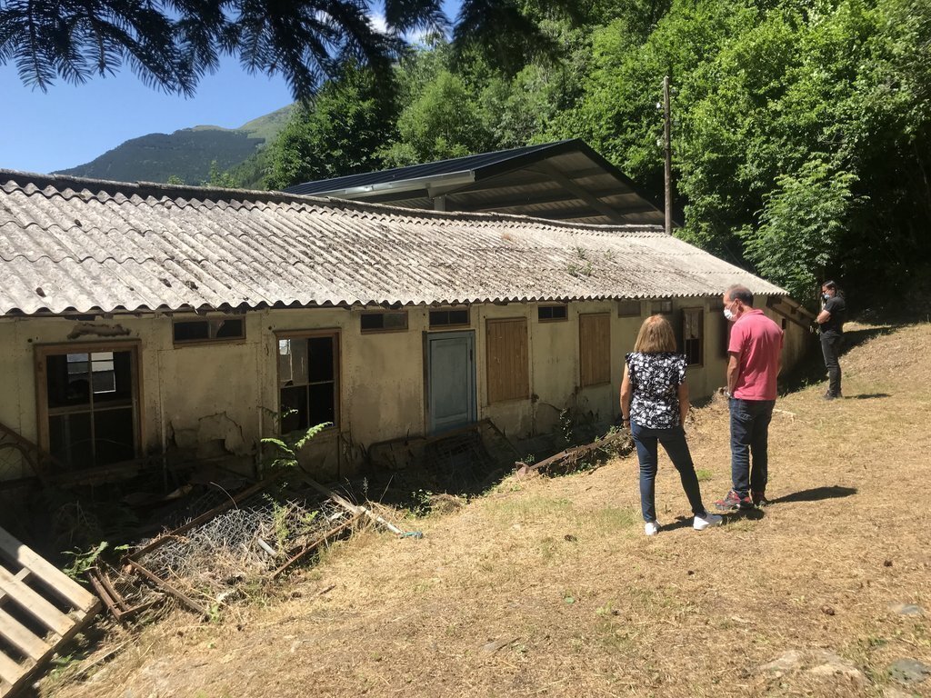 Pla obert on es veuen diversos veïns visitant l'exterior de l’Hospital de cartró de la Vall Fosca. Imatge del 9 de juliol de 2021. (Horitzontal)