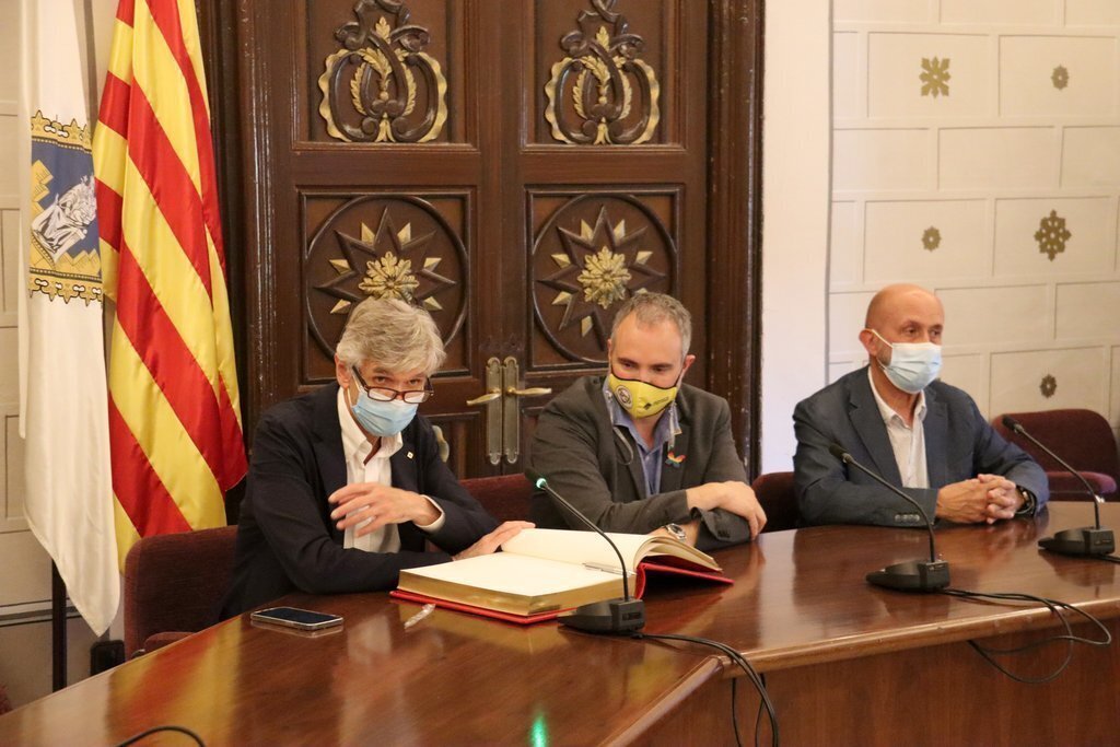 Pla obert del conseller de Salut, Josep Maria Argimon, signant el llibre d'honor de l'Ajuntament de la Seu d'Urgell amb l'alcalde al costat, Jordi Fàbrega i el ministre de Salut andorrà, Joan Martínez Benazet. imatge del 9 de juliol de 2021. (Horitzontal)