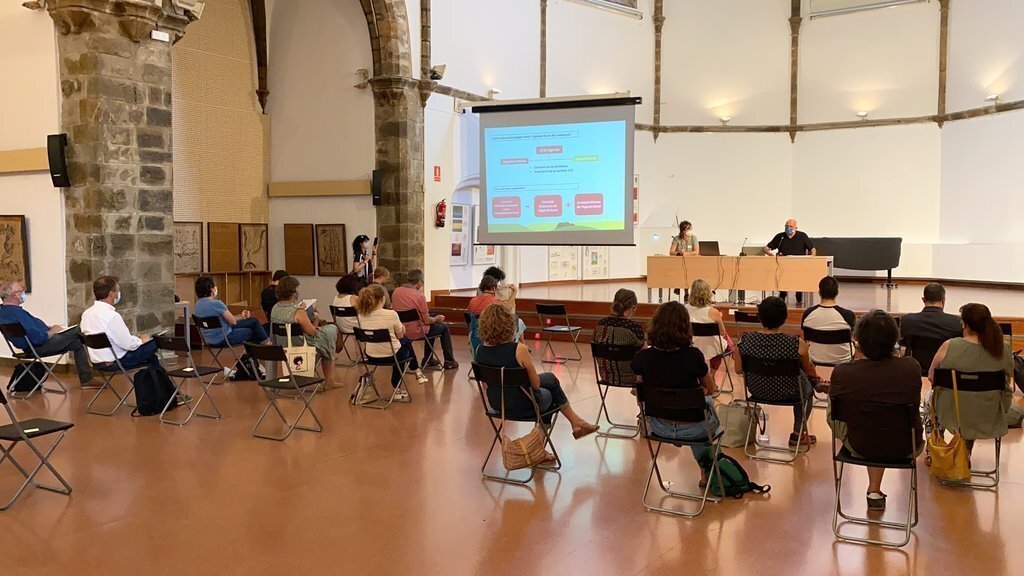 Pla obert on es veuen els participants al taller territorial de l'Agenda Rural de Catalunya dut a terme a la Seu d'Urgell i un dels membres de la comissió redactora del document, Lluís Corominas, fent una presentació, el 12 de juliol de 2021 (Horitzontal)