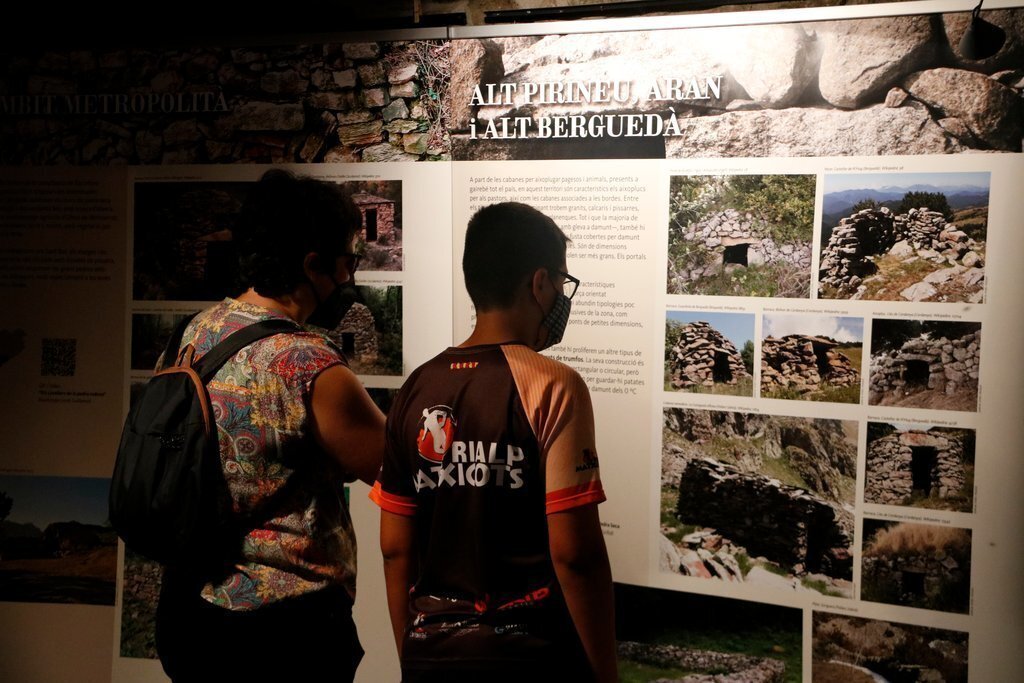 Pla de detall de dos persones a l'exposició de la pedra seca a l'Ecomuseu de les Valls d'Àneu el 17 d'agost del 2021. (Horitzontal)