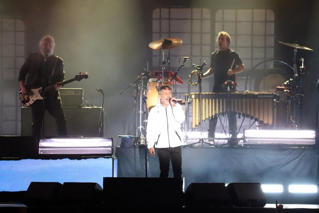 Pla obert on es veu al cantant de Love of Lesbian amb part dels integrants del grup actuant a la zona de l'auditori del Cerdanya Music Festival, en un espai natural d'Alp (Cerdanya). Imatge del 23 d'agost de 2021. (Horitzontal)