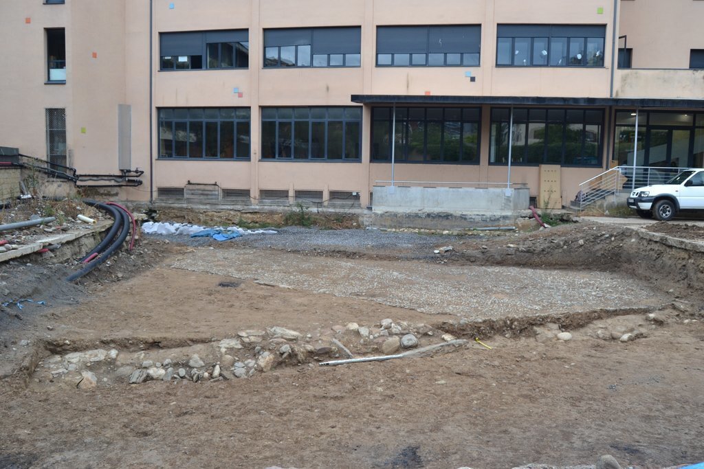 Pla obert del jaciment del pati de les Monges de la Seu d'Urgell on es veu en primer terme el tram de la muralla baix medieval descobert durant les tasques de delimitació de la zona arqueològica. Imatge del 9 de setembre de 2021. (Horitzontal)